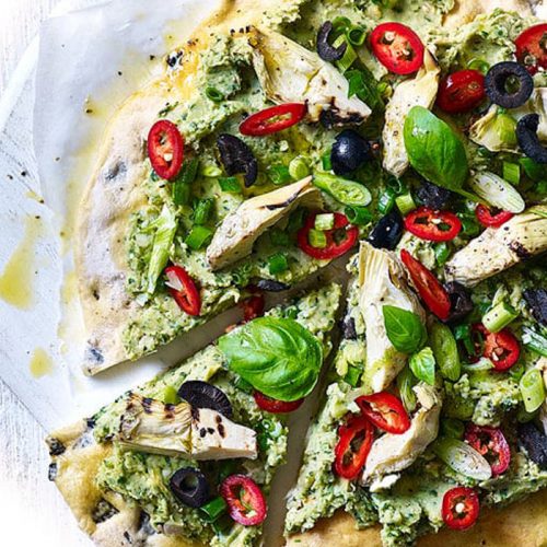 Vegan pizza with an olive crust and avocado and butter bean topping